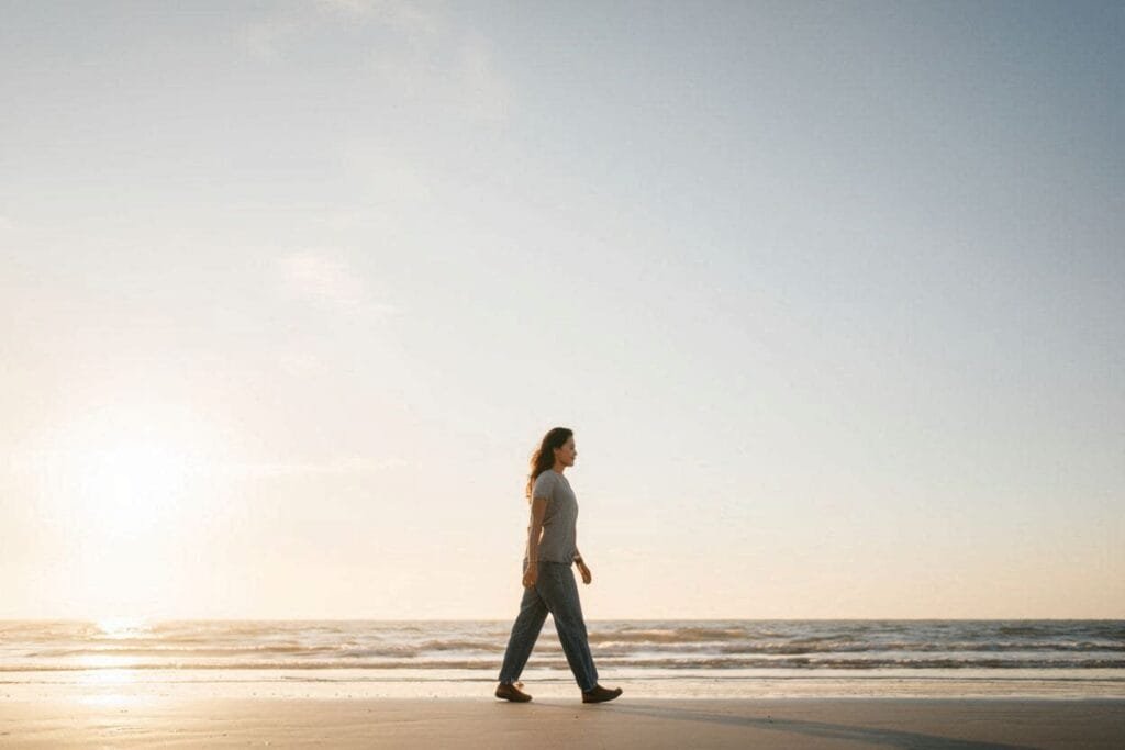 Persona caminando en la playa al atardecer, representando calma, claridad y alivio emocional al trabajar ansiedad.